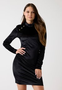 Czarna aksamitna sukienka z długim rękawem, wysoka szyja i ozdobne złote guziki na ramieniu, z dopasowanym krojem i miękką teksturą.
