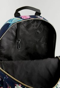 Rucsac cu fermoar, cu un exterior cu model floral în nuanțe de albastru și negru. Interiorul este de culoare neagră, având o textură netedă și un mic clip pentru prinderi.