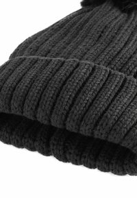 Berretto lavorato a maglia nero con un design a coste. Realizzato in morbida lana, presenta un bordo spesso e un pon-pon sulla cima. Dettagli della superficie testurizzati visibili.