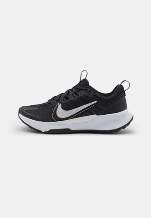 Black athletic shoes with a textured upper, featuring a white swoosh logo, a cushioned sole, and a pull tab on the heel for easy wearing.