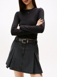 Svart langermet topp med ribbet tekstur og lite logo, parret med en svart denim plisserte skjørt og et svart belte med sølvspenne.