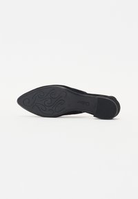 Escarpin en suède noir avec un bout pointu, une semelle lisse, des accents texturés subtils et un design courbé sur la semelle extérieure.