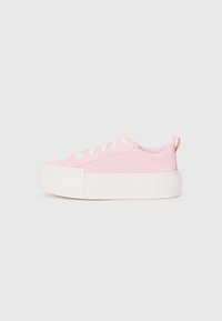 Baskets en toile rose avec une surface texturée, bout rond et semelle en caoutchouc blanc épais. Dotées de lacets blancs et d'une poignée au niveau du talon.