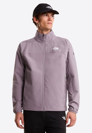 Chaqueta de color púrpura claro con cuello alto, cremallera frontal y tejido texturizado. Cuenta con un logo en el pecho y un bolsillo con cremallera en la manga.