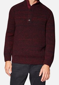 Pull tricoté bordeaux et noir avec fermeture à boutons au niveau du col, poignets côtelés et motif texturé, porté par-dessus une chemise à col.