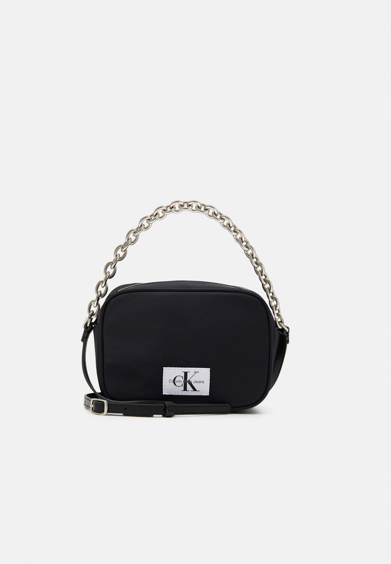 Bolso rectangular negro hecho de nylon, con un asa de cadena, correa ajustable y una parche de marca que presenta las iniciales "CK."