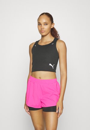 Zwart crop top met textuurstof en wit logo, gecombineerd met felle roze sportshorts met een elastische tailleband.