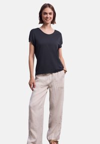 Černé tričko s krátkým rukávem a kulatým výstřihem, v kombinaci s volnými béžovými kalhotami s kapsami. Měkká látka, neformální styl.