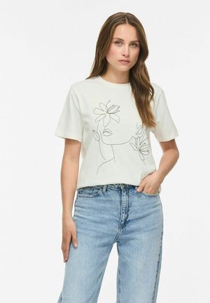 Kvinde med langt brunt hår iført en hvid T-shirt med minimalistisk linjekunst af et ansigt og blomster, kombineret med lyseblå jeans.