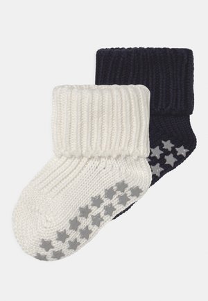Calze lavorate a maglia in bianco e blu navy, con risvolto a costine e suole testurizzate decorate con motivi a stella grigi per una maggiore aderenza. Tessuto morbido e accogliente.