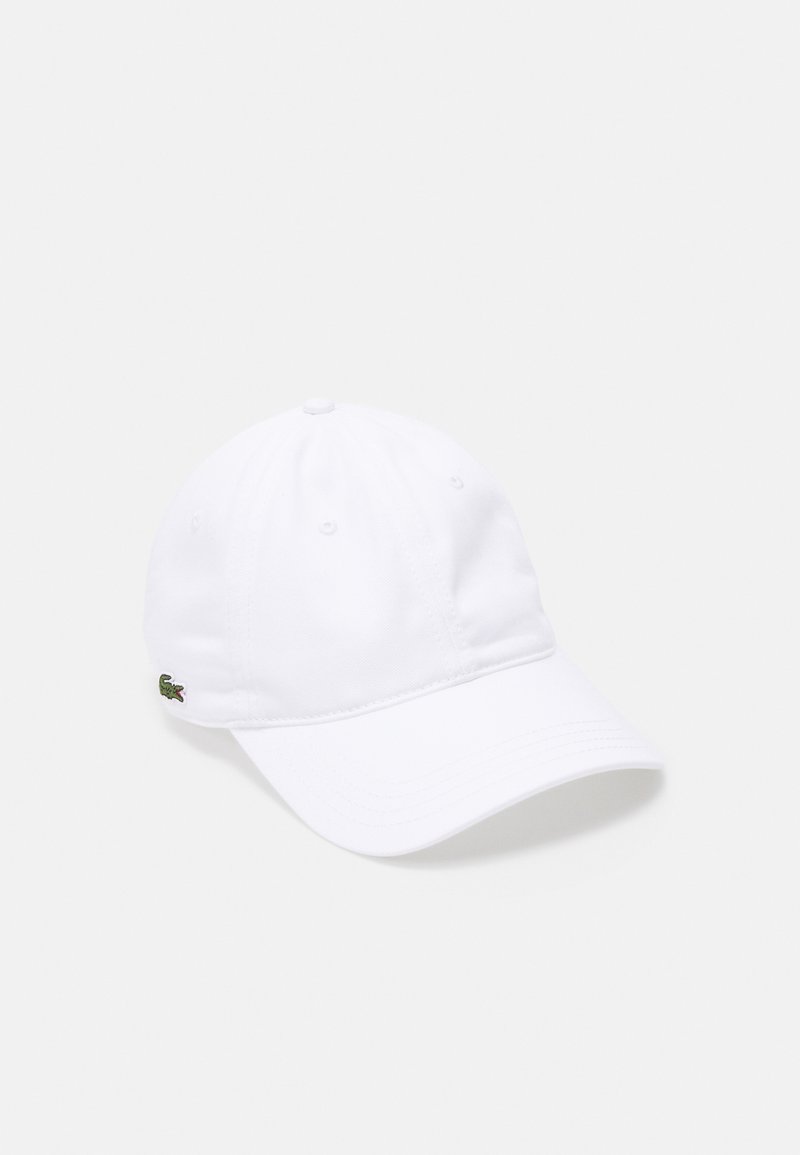 Hvit baseballcaps laget av bomull med sydd ventilasjonshull; har en liten grønn krokodillelogo på siden.