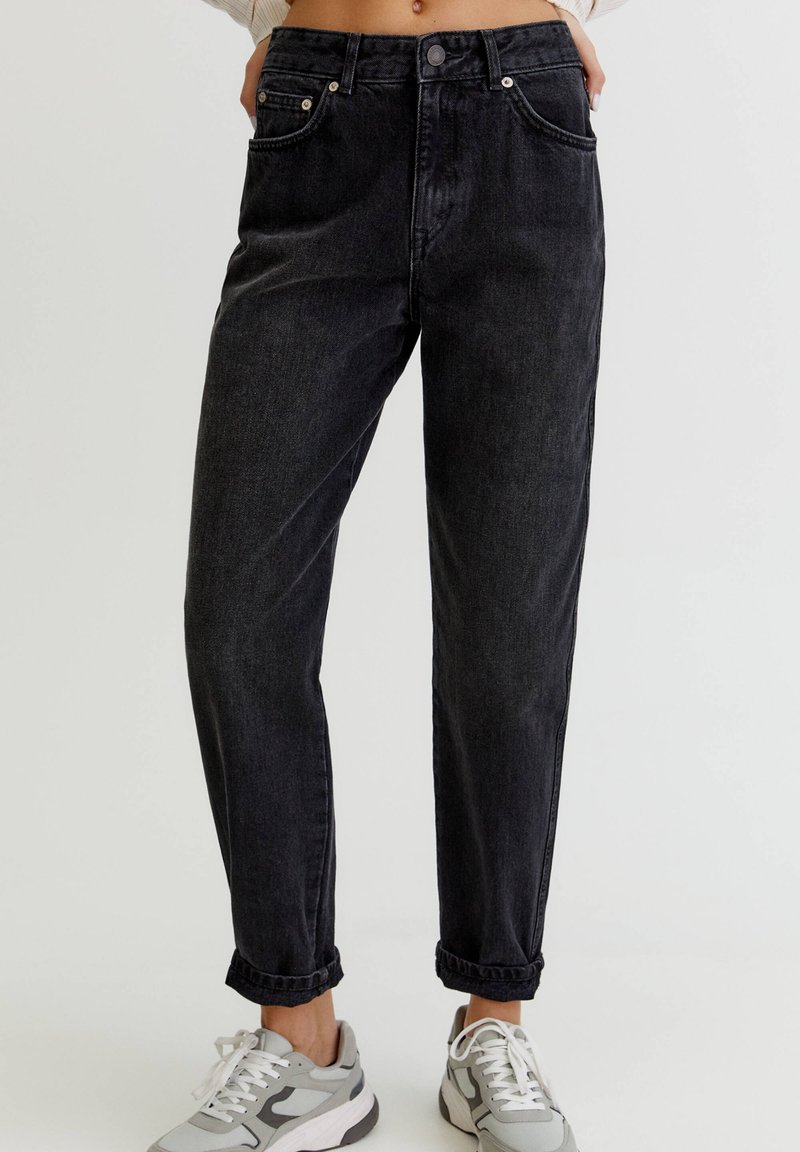 Jeans de mezclilla negros con cintura alta, pierna recta y dobladillos enrollados. Incluye bolsillos delanteros y detalles en botón plateado.