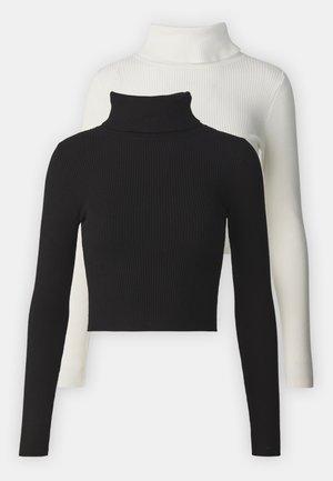 Two ribbed turtlenecks: one black, one white. Both have long sleeves and a cropped cut, featuring a soft, textured fabric.