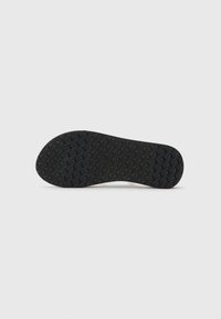 Black rubber outsole with a textured pattern featuring raised star shapes, designed for grip and durability. Curved edges with a smooth transition.