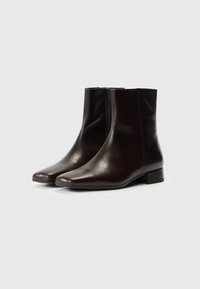 Pruunid nahast pahkluu saapad elegantse disainiga, teravate varvaste, külgsete tõmblukkude ja madalate plokk-kontsadega. Sile pind väheste detailidega.