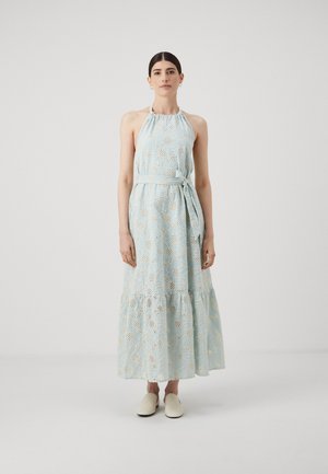 Lichtblauwe, mouwloze maxi-jurk met bloemen uitsnijdpatroon, een halterhalslijn, een getailleerde taille en een gelaagde rok. Draagt met witte instappers.