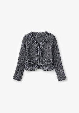 Chaqueta corta con patrón en blanco y negro, mangas largas, bordes deshilachados y dos bolsillos delanteros sobre un fondo blanco.