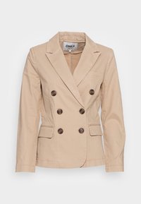 Beżowa marynarka dwurzędowa wykonana z miękkiego materiału, z dużymi brązowymi guzikami, kołnierzem z wycięciem i dwoma przednimi kieszeniami.