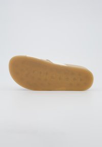 Tan rubber sandaalonderzijde met een gestructureerd oppervlak en cirkelvormige grippatronen. Bevat het verhoogde merk "Paul Green." Glad afgewerkte randen.