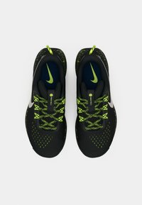 Crne sportske tenisice s neonsko zelenim detaljima, s teksturiranim gornjim dijelom, okruglim vezicama i istaknutim logotipom swoosh sa strane.