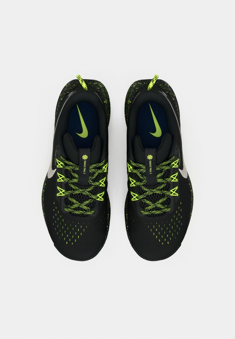 Zapatillas deportivas negras con detalles en verde neón, que presentan una parte superior texturizada, cordones redondos y un logo swoosh prominente en el lateral.