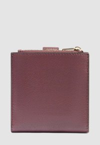 Portafoglio in pelle bordeaux con finitura testurizzata, forma quadrata, chiusura superiore con zip e accessori in tonalità dorata.