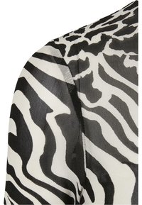 Zwart-witte stof met zebraprint in een gestructureerde uitstraling. Heeft gedurfde, golvende patronen en een gladde, lichtgewicht materiaal.