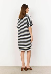 Striped dress in navy and cream; loose fit with short sleeves, knee-length hem, and side slits. Paired with brown block-heeled sandals.