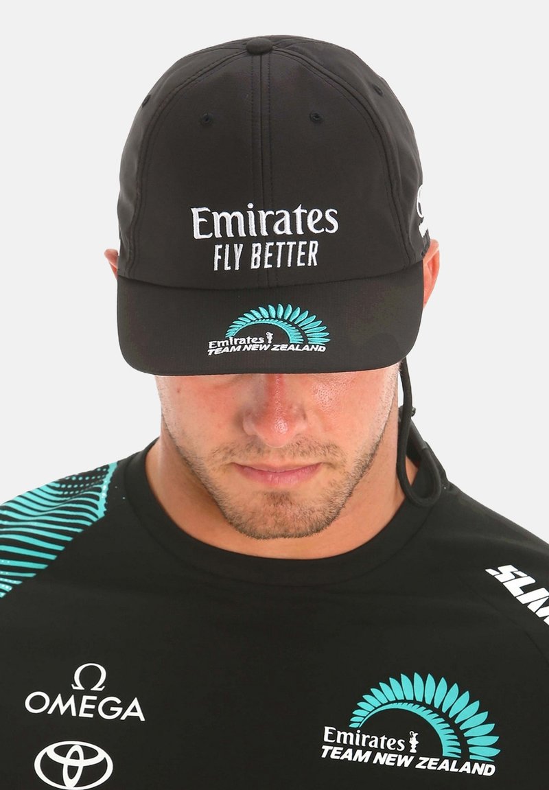 Cappello nero con la scritta "Emirates FLY BETTER" in bianco, logo ricamato in turchese. Visiera corta, materiale leggero, progettato per l'abbigliamento sportivo.