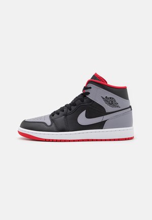 Sort og grå high-top Nike Air Jordan sneaker med røde accenter og hvid sål vist fra siden på en hvid baggrund.