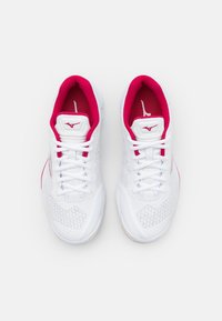 Białe buty sportowe z siateczkową cholewką, różowymi akcentami na kołnierzu i logo oraz teksturowaną gumową podeszwą. Sześć przelotek na sznurowadła zapewniających pewne dopasowanie.