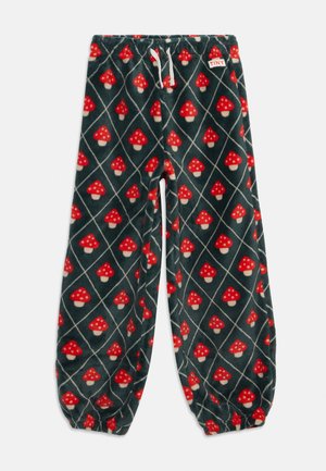 Pantalon en polaire vert foncé avec motif champignons rouge et blanc, chevilles élastiques, cordon blanc et étiquette "TINY" à la taille.