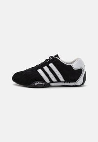 Melnas zamšādas sporta kedas ar trim baltām svītrām, elegants dizains, noapaļots purngals un melna gumijas zole, uz sāniem ar Adidas logo.