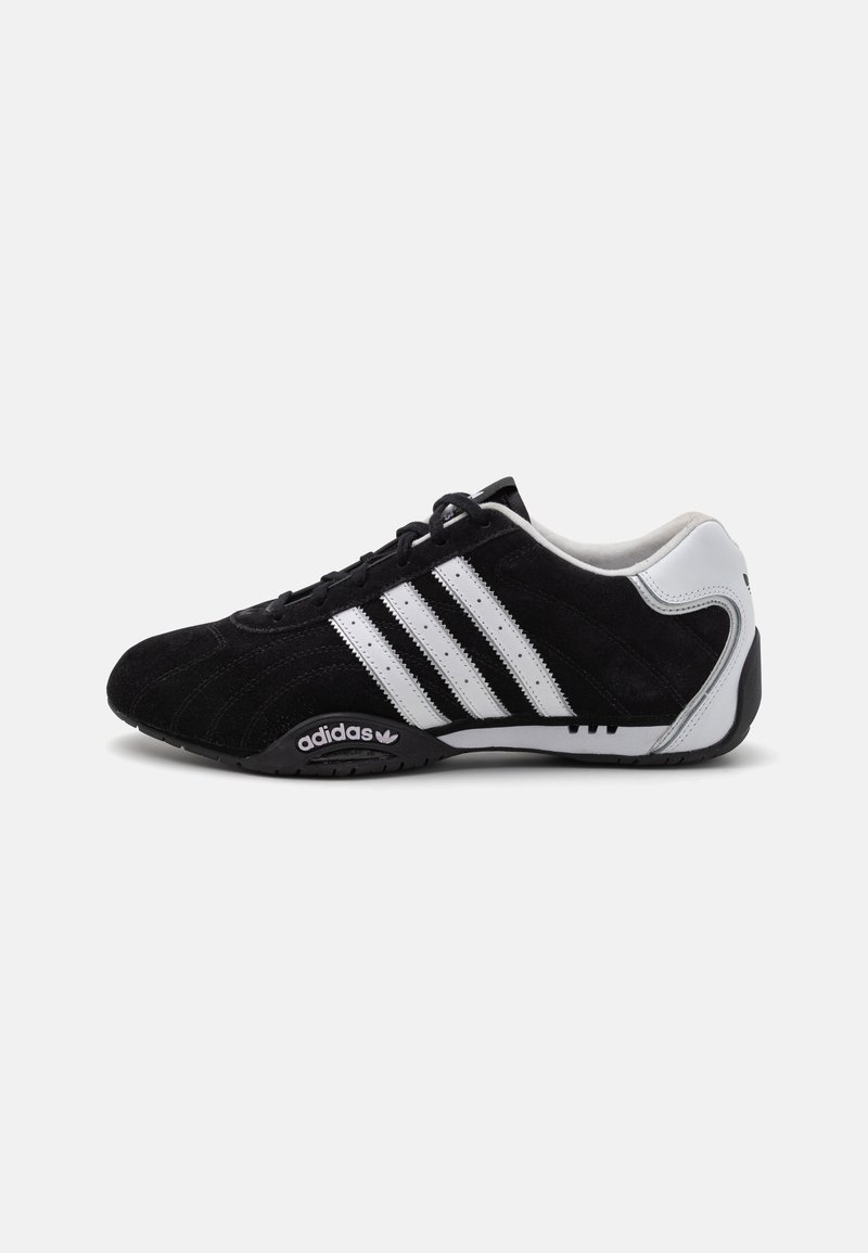 Melnas zamšādas sporta kedas ar trim baltām svītrām, elegants dizains, noapaļots purngals un melna gumijas zole, uz sāniem ar Adidas logo.