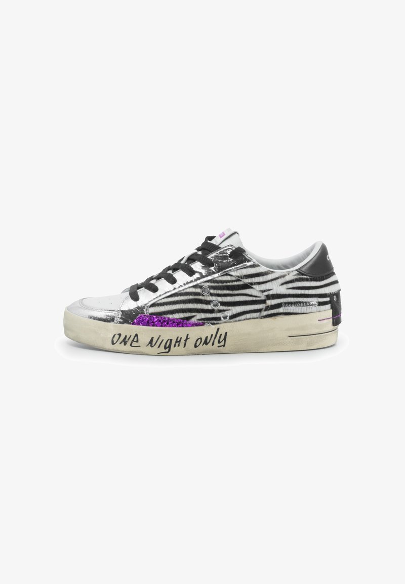 Sneakers a strisce bianche e nere con punta argentata lucida, dettagli glitter viola, lacci neri e la scritta "ONE NIGHT ONLY" sul lato.