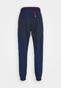 Marineblaue Jogginghosen mit einem strukturierten dunkelblauen Paneel, elastischem Bund mit roten Akzenten und Knöchelbündchen, ausgestattet mit einer Reißverschlusstasche.