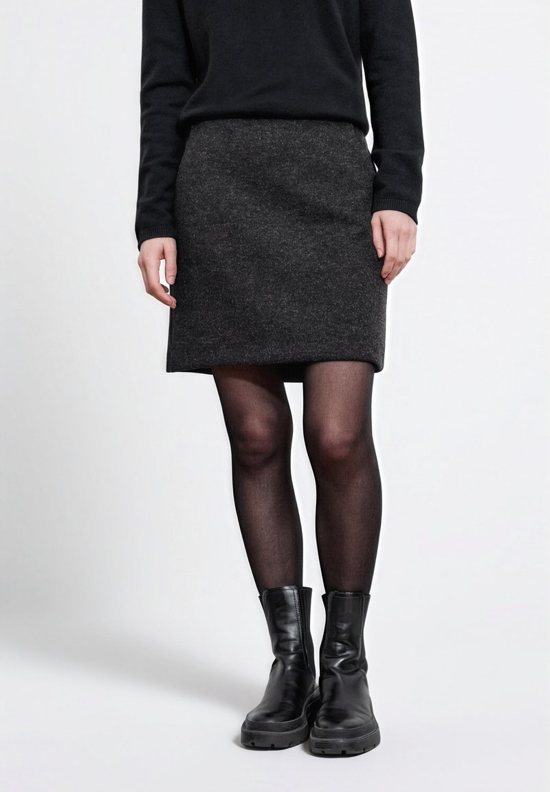 Harmaa villahame, jossa on suora leikkaus, käytettuna mustien läpinäkymättömien legginsien ja mustien nilkkabootsien kanssa. Asusteessa on yksinkertainen ja siisti muotoilu.