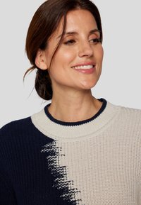 Strickpullover mit einem zweifarbigen Design in Marineblau und Creme. Der strukturierte Stoff hat einen runden Halsausschnitt und gerippte Akzente.