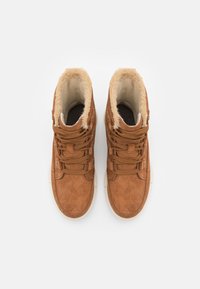 Zapatillas altas de ante marrón con forro de piel sintética, cordones y acentos circulares en los laterales; suela de goma blanca.