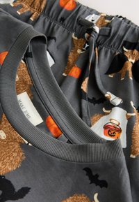 Shorts gris avec un motif ludique d'animaux, de citrouilles et de chauves-souris, fabriqués en tissu doux avec une taille élastique et un cordon de serrage.