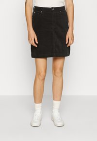 Svart kordknotad kjol med rak skärning, framknäppning och två sidofickor. Bärs med vita sneakers och texturerade strumpor.