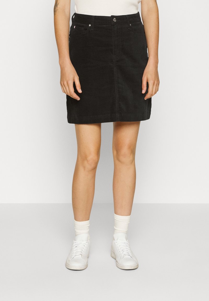 Svart kordknotad kjol med rak skärning, framknäppning och två sidofickor. Bärs med vita sneakers och texturerade strumpor.
