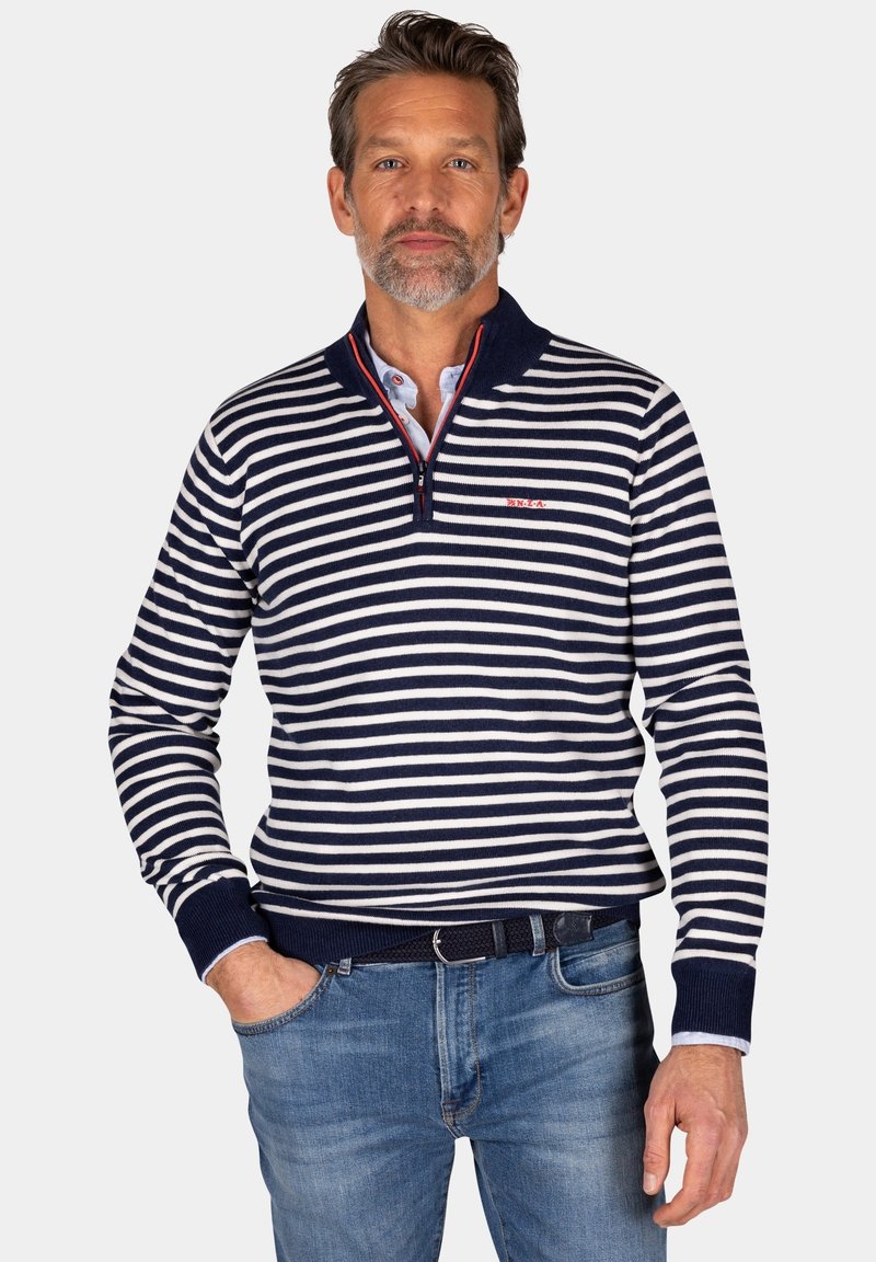Marineblauw en witte gestreepte pullover van een zachte breimateriaal, met een ritskraag en geribde manchetten. Gecombineerd met blauwe jeans.