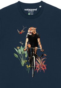 Marineblauwe t-shirt met een fietser met een tijgerkop, omringd door geïllustreerde bloemen en planten in levendige kleuren.