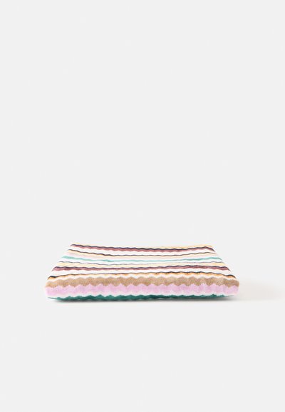 Tissu rayé plié avec des lignes ondulées horizontales en marron, rose, orange, vert, bleu et blanc sur un fond blanc uni.