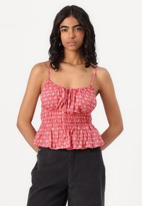 Rdeč peplum top s cvetličnim potiskom, tankimi naramnicami, zgornjim delom s smoki in naboranim robom. Tkanina je lahka in je vzorčena z geometrijskimi akcenti.