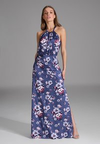 Robe fleurie longue en bleu marine avec un décolleté halter. Présente des fleurs blanches et bourgognes, un tissu fluide et une fente sur le côté. Détails argentés sur les chaussures.