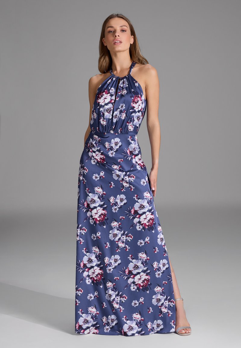 Robe fleurie longue en bleu marine avec un décolleté halter. Présente des fleurs blanches et bourgognes, un tissu fluide et une fente sur le côté. Détails argentés sur les chaussures.