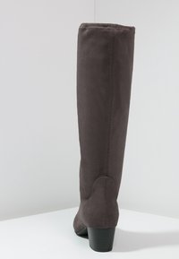 Bota gris de ante hasta la rodilla con forma tapered, tacón de bloque y una textura suave con un detalle de costura en la parte trasera.