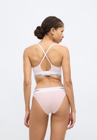 Ροζ βαμβακερό σουτιέν με διασταυρούμενους ιμάντες και λωρίδα με το λογότυπο Calvin Klein, συνδυασμένο με ταιριαστά εσώρουχα που έχουν λευκή μέση.